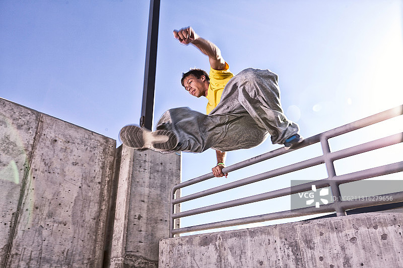 在城市中跳过墙壁的男性跑酷运动员图片素材