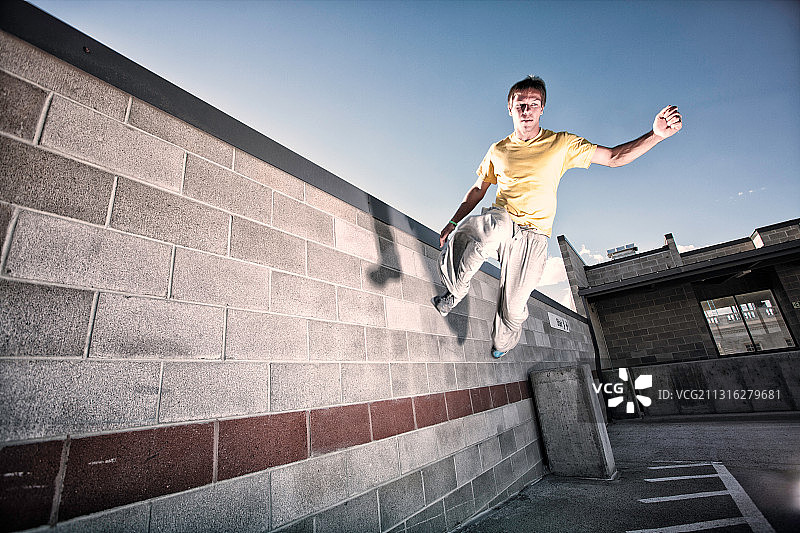 城市中在水泥墙上跳跃的年轻男子跑酷运动员图片素材