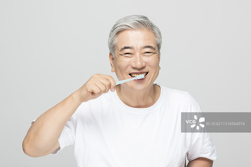 中年男人在灰色背景下刷牙微笑图片素材