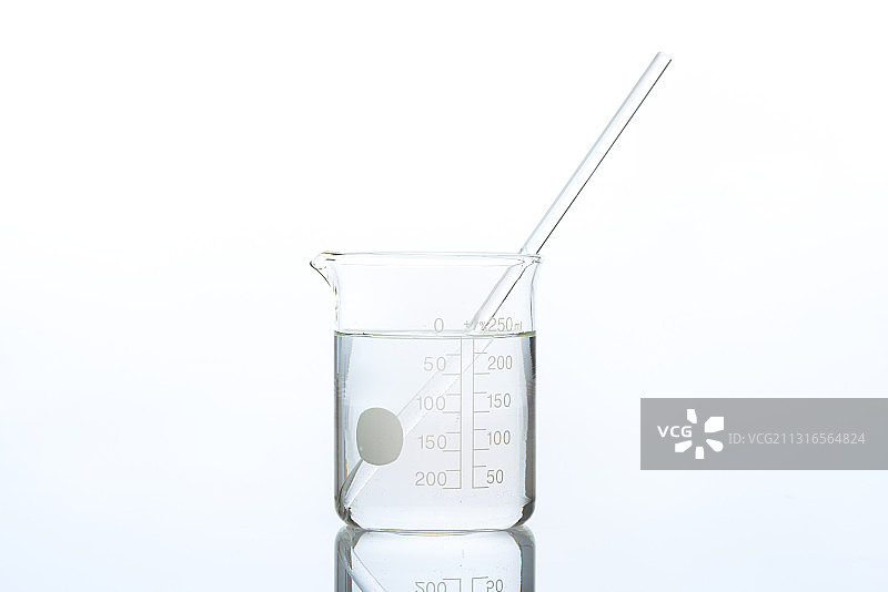 烧杯中带有玻璃搅拌棒的透明液体图片素材