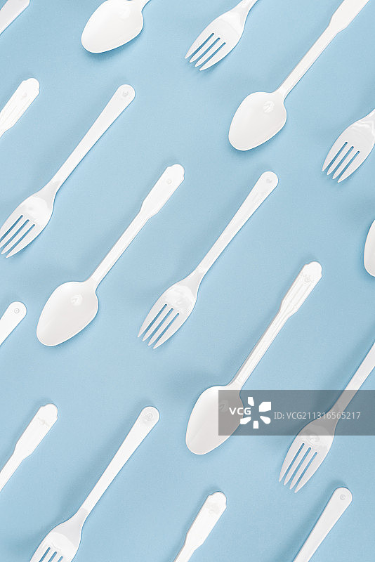 蓝色背景上成排的塑料勺子和叉子图片素材