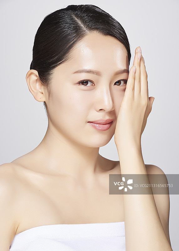 穿着白色露脐装的女人用手遮住灰色背景上半张脸图片素材