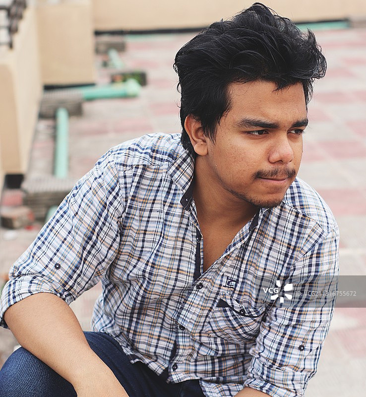 坐在台阶上望向远方的年轻人，达卡，孟加拉国图片素材