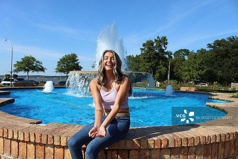 微笑的女人坐在游泳池旁图片素材