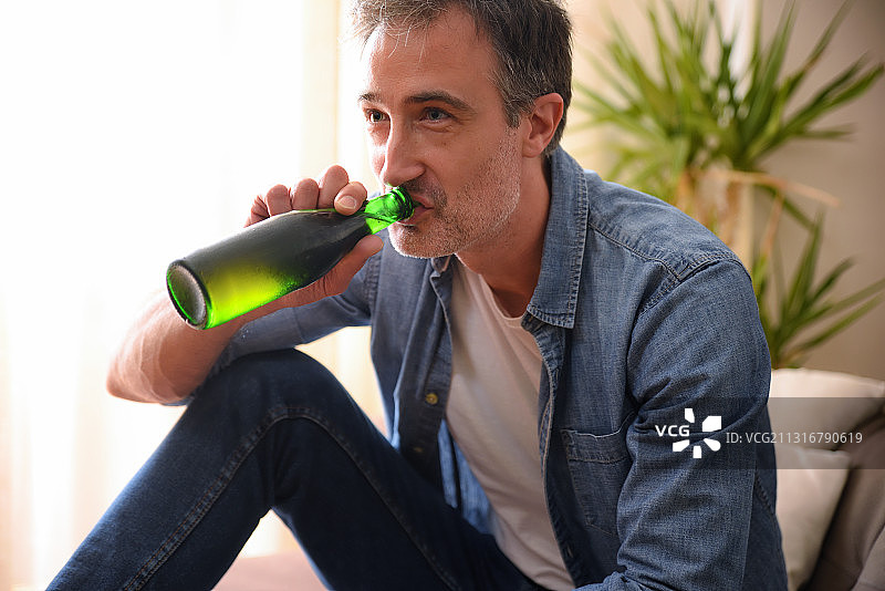 男人在家中沙发上喝瓶装水图片素材