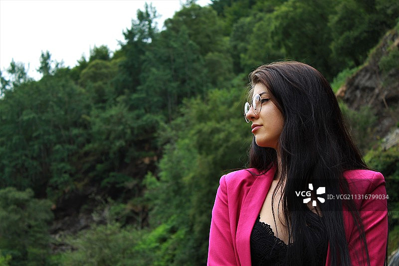 年轻女子站在树旁向远处眺望图片素材