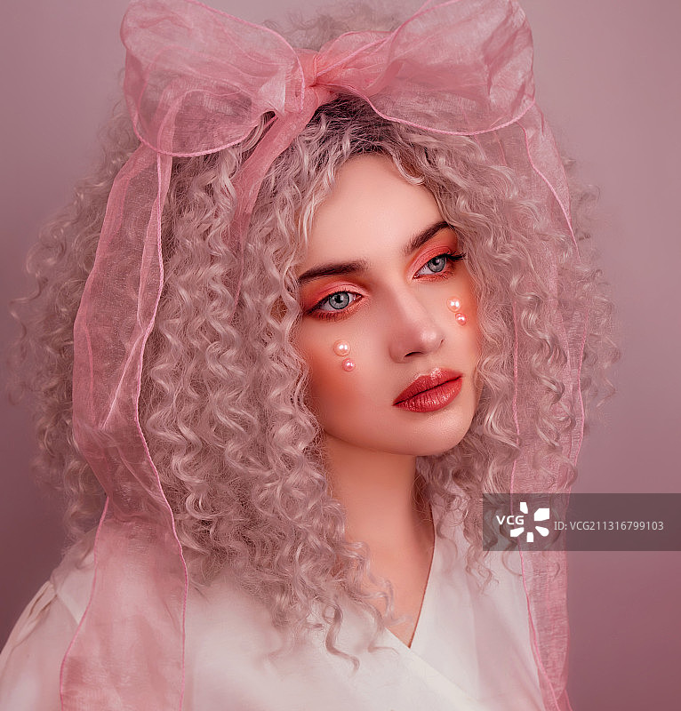 粉色背景下，化粉色妆容的年轻女子肖像图片素材