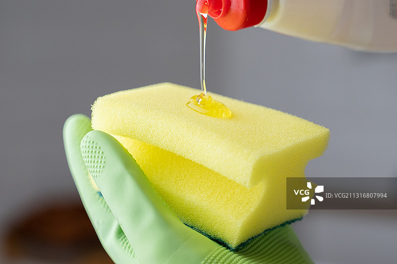 一人将洗涤剂倒在海绵上的局部照片图片素材