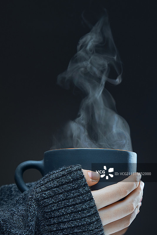 女子在黑色背景下手捧茶杯图片素材