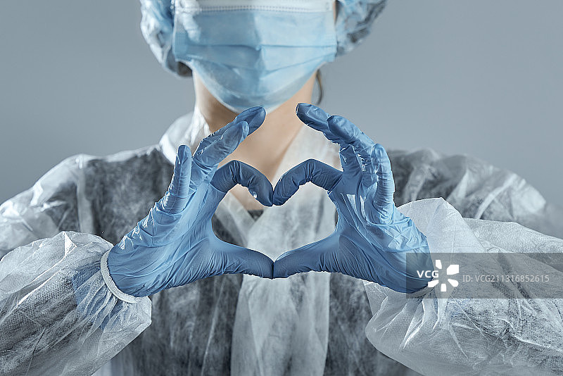 身穿医疗防护装备的女子用手做出心形的腰部特写图片素材