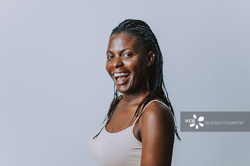 灰色背景前的微笑年轻女子肖像图片素材