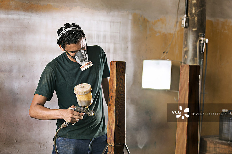 年轻男人喷涂木制家具图片素材