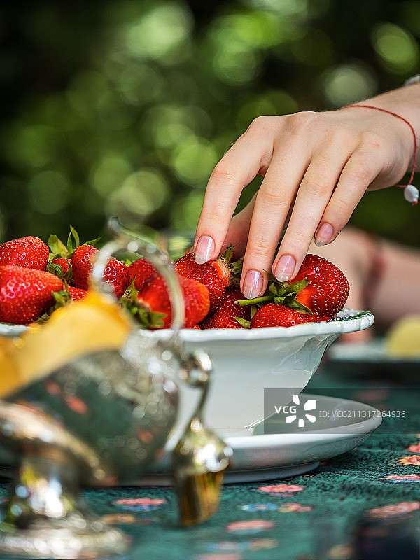 女子伸手去拿碗里的草莓图片素材