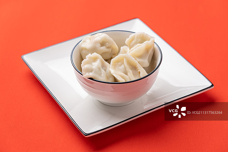 红色背景节日气氛喜庆概念一碗刚煮熟的饺子图片素材