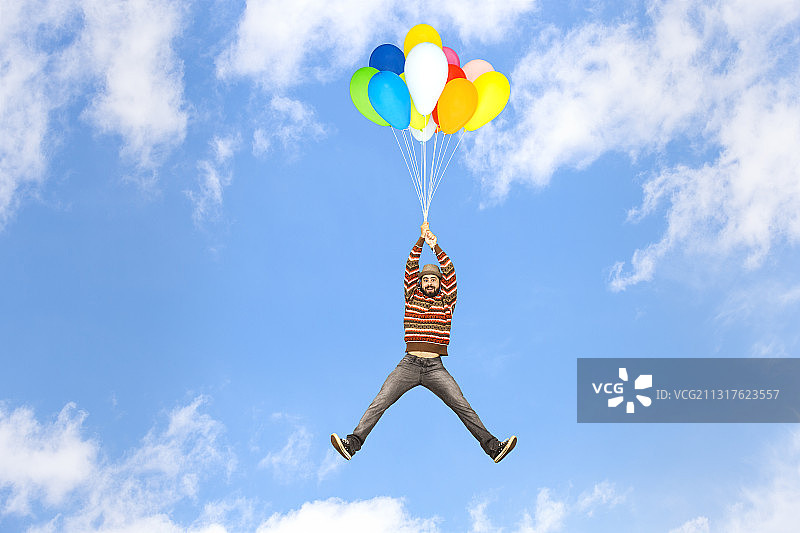 带着气球在天空飞翔的年轻男子图片素材