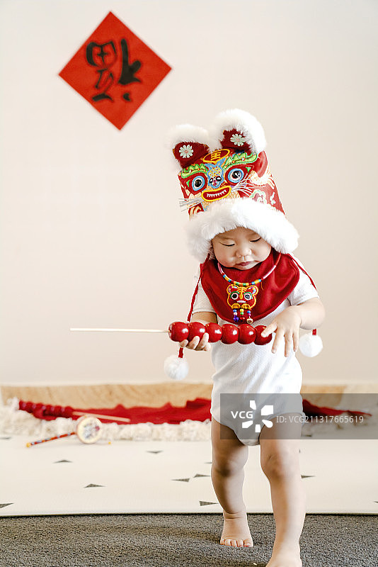 新年戴老虎帽的开心娃拿着糖葫芦串图片素材