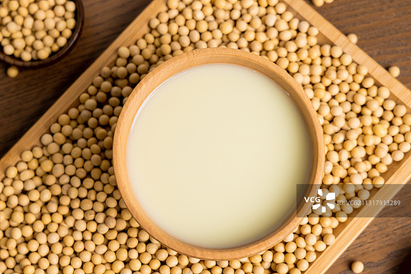 纯色桌子上碗里的早餐豆浆饮品和原材料黄豆图片素材