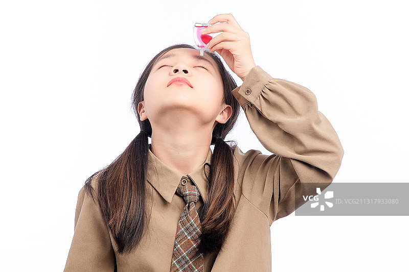 白色背景里，正在使用眼药水的亚洲小女孩图片素材