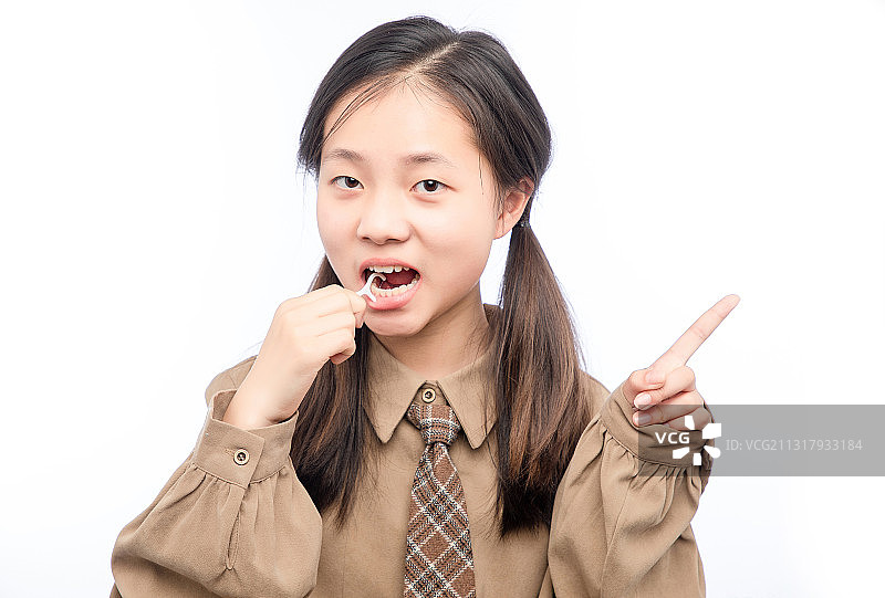 白色背景里，正在使用牙线的亚洲小女孩图片素材