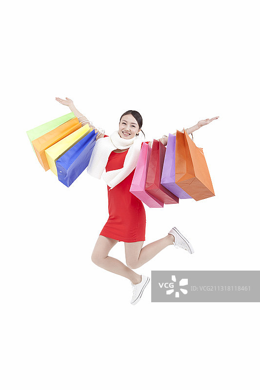 快乐的女人提着购物袋站在白色背景前的肖像图片素材