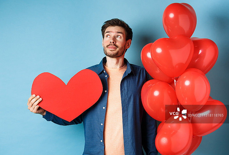 男人在蓝色背景下手持心形的肖像图片素材