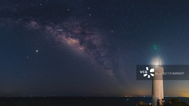 夜空下，灯塔与银河熠熠生辉。图片素材