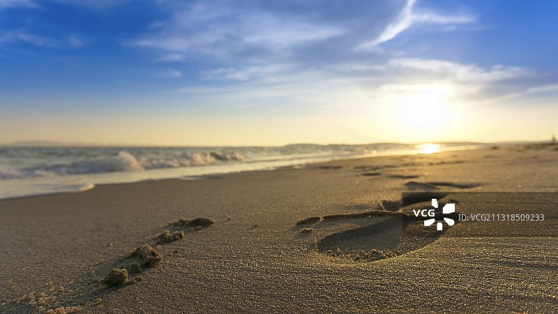 日落时沙滩上的脚印特写图片素材
