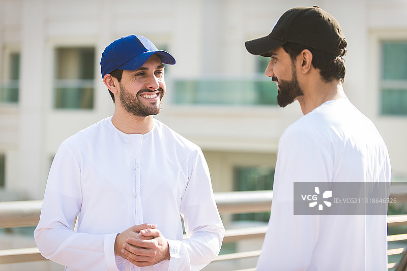 两位戴着棒球帽的阿拉伯男人在阿拉伯联合酋长国迪拜的城市里图片素材