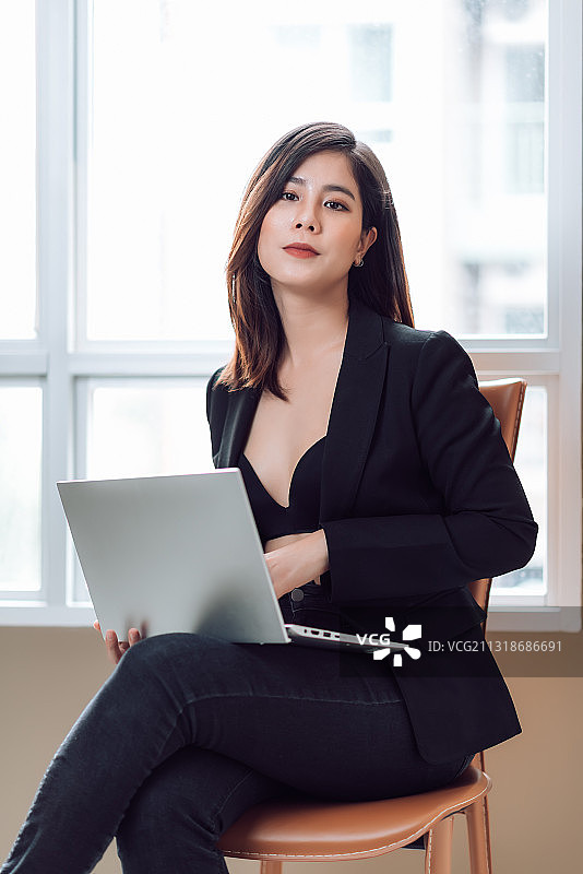 坐在椅子上使用笔记本电脑的年轻女商人肖像图片素材