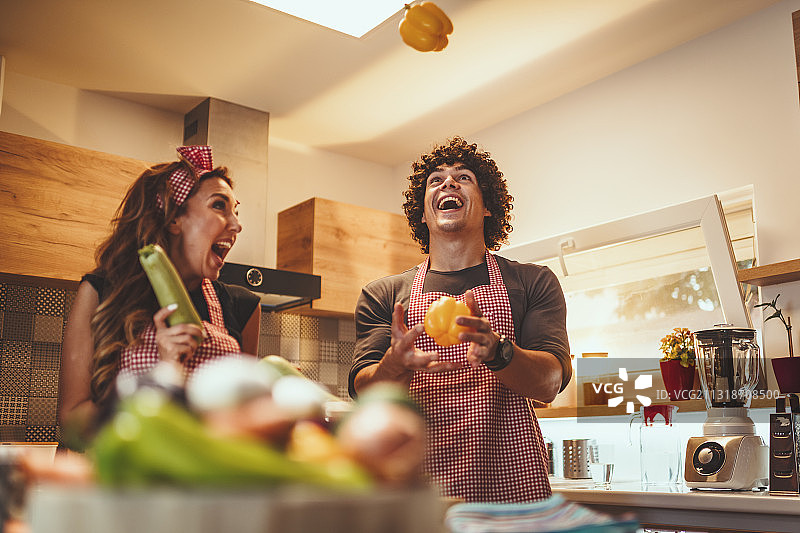 快乐的年轻情侣在厨房一起烹饪美食，塞尔维亚，诺维萨德图片素材