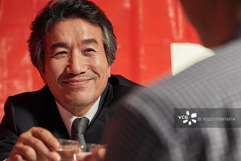 父亲和儿子举起烧酒杯，开怀畅饮图片素材