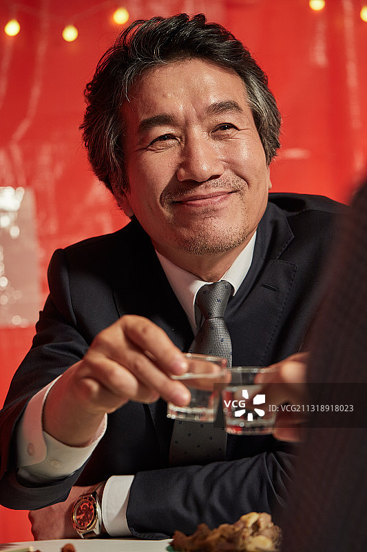 父亲和儿子举起烧酒杯，开怀畅饮图片素材