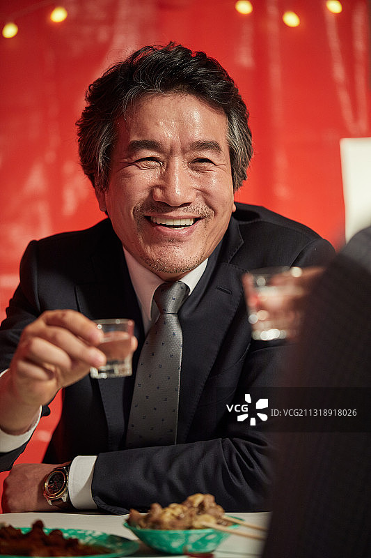 父亲和儿子举起烧酒杯，开怀畅饮图片素材