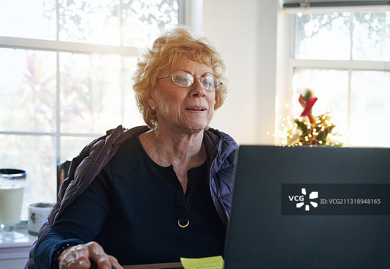 为降低风险在家使用笔记本电脑的年长女性图片素材