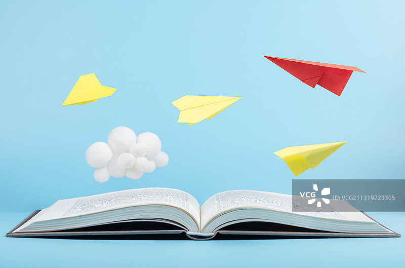 蓝色天空书本上飞翔的纸飞机与可爱的云朵图片素材