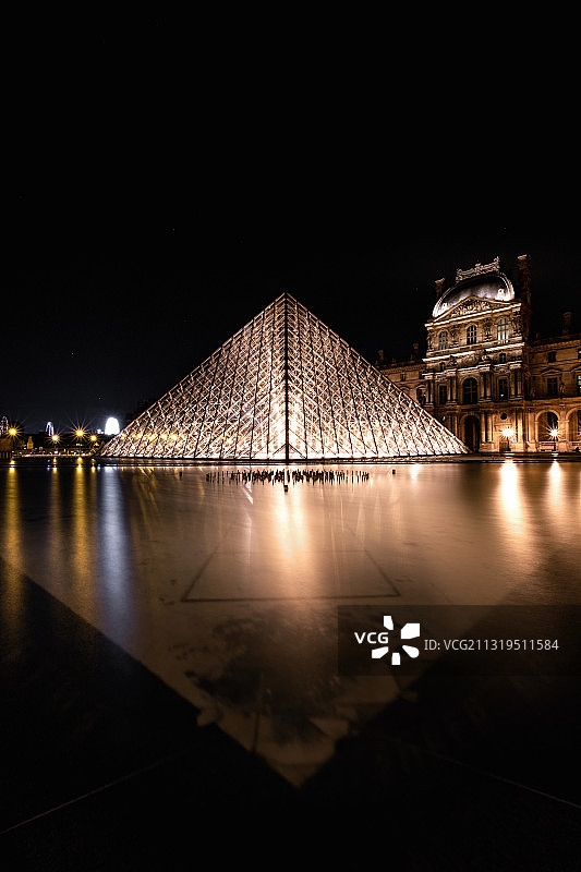 法国巴黎卢浮宫夜景：玻璃金字塔与喷泉倒影图片素材