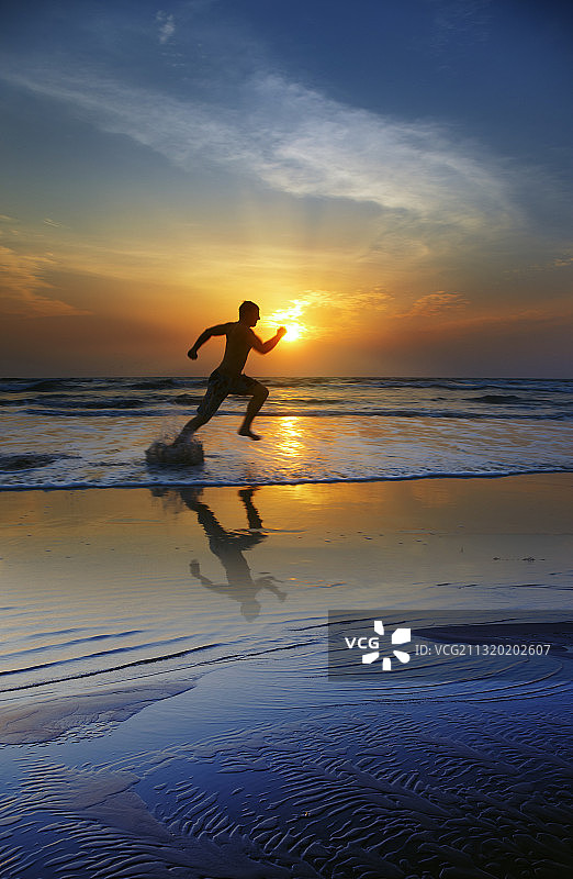 男人在日落时分的海滩跑步图片素材
