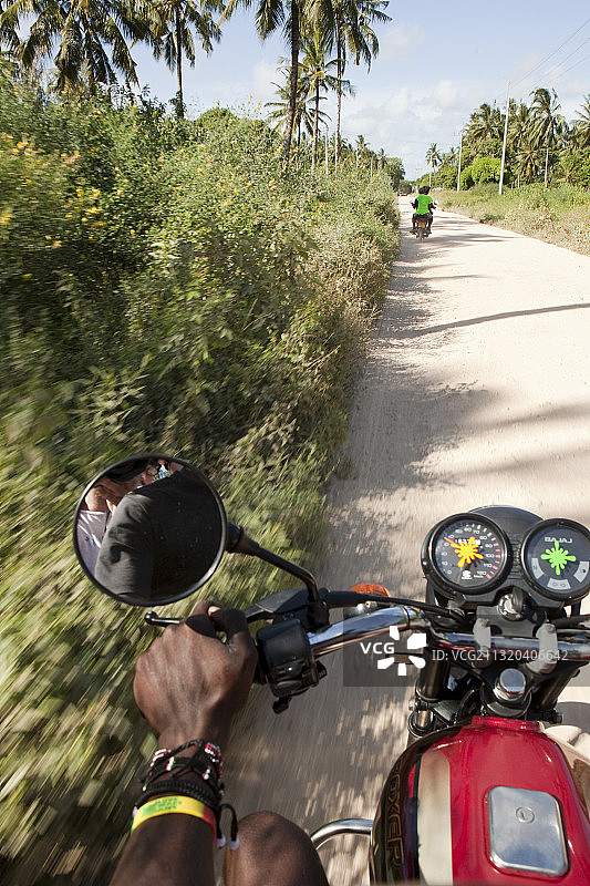 骑摩托车穿过肯尼亚马林迪瓦塔穆的椰子种植园图片素材