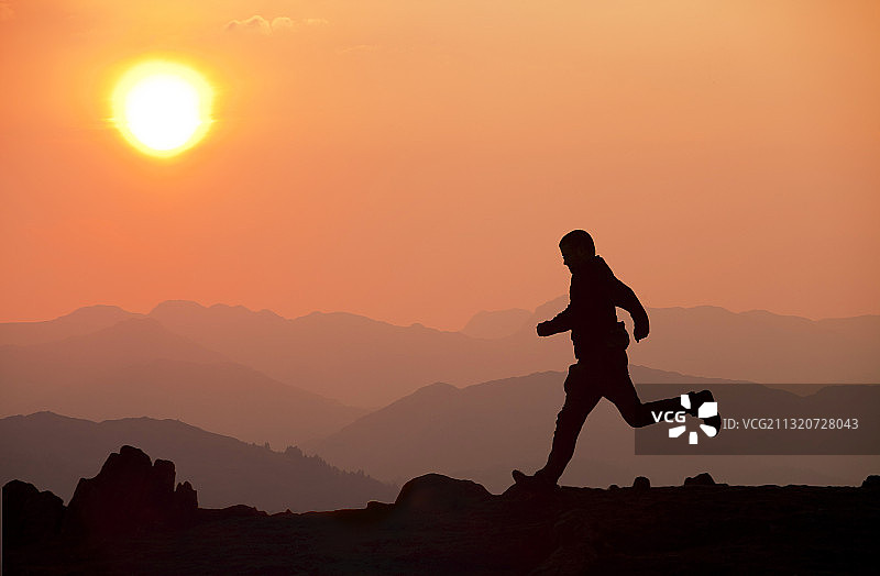 英国温德米尔湖区山脉日落，一名男子跑过图片素材