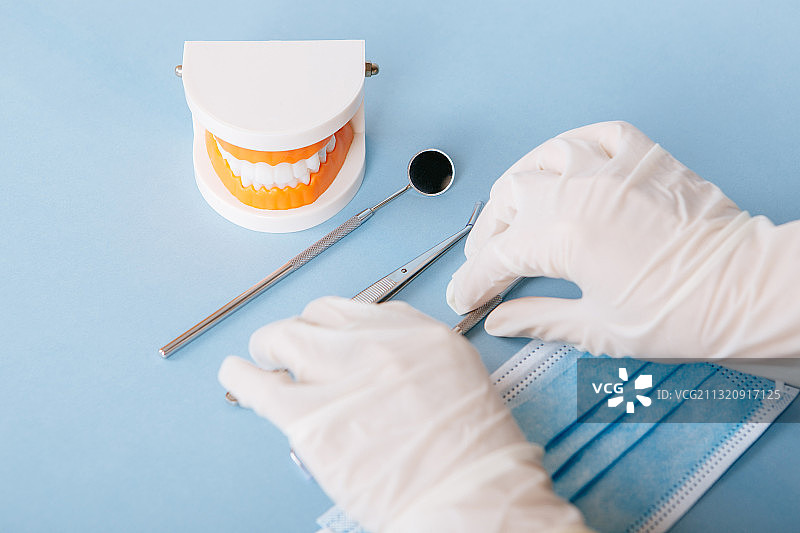 医疗手套的手拿着牙医看牙治疗牙齿疾病的工具图片素材