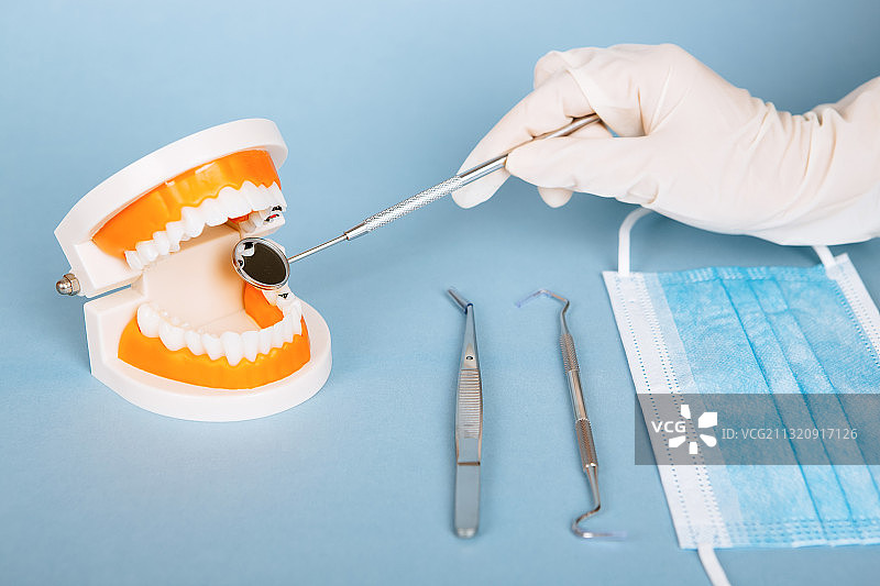 医疗手套的手拿着牙医看牙治疗牙齿疾病的工具图片素材