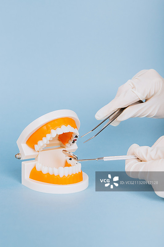 医疗手套的手拿着牙医看牙治疗牙齿疾病的工具图片素材