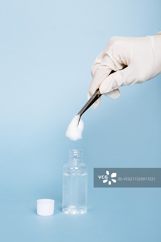 医用手套拿着镊子用棉花蘸取消毒酒精图片素材