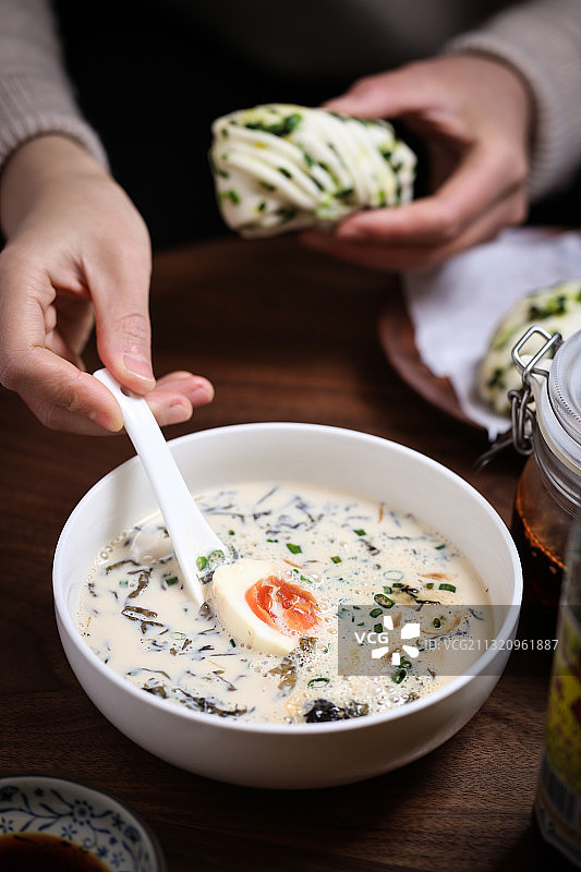 手拿勺子和花卷馒头吃中式传统早餐图片素材