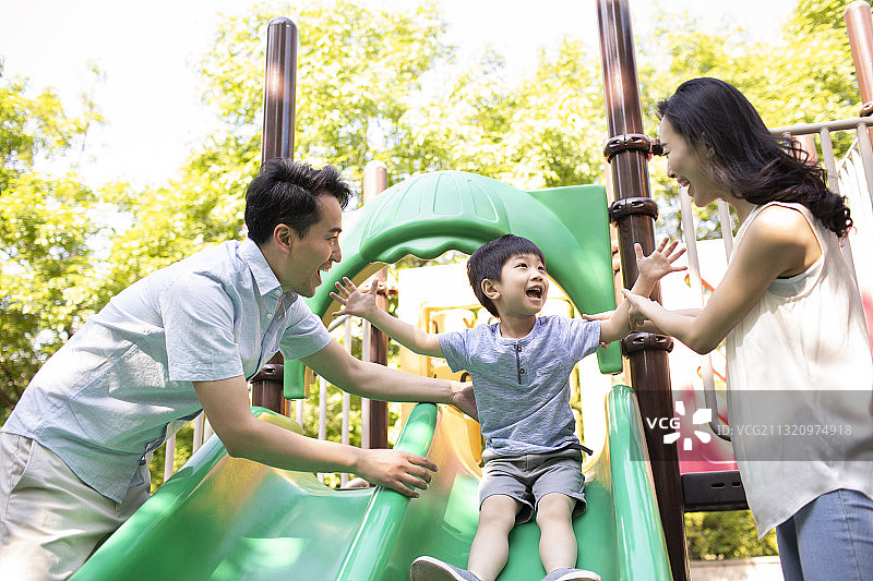 年轻家庭在游乐园滑滑梯图片素材
