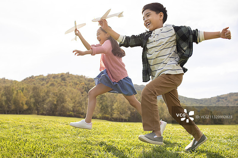 快乐的的姐弟俩在草地上玩耍图片素材