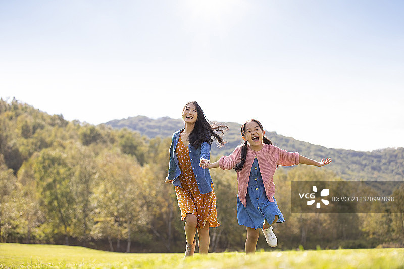 快乐的的母女俩在草地上玩耍图片素材