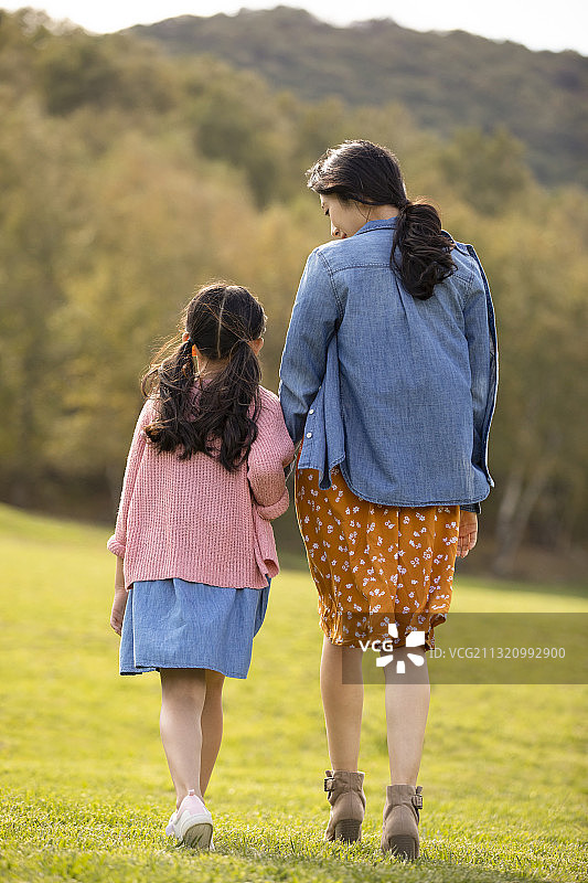 快乐的的母女俩在草地上散步图片素材