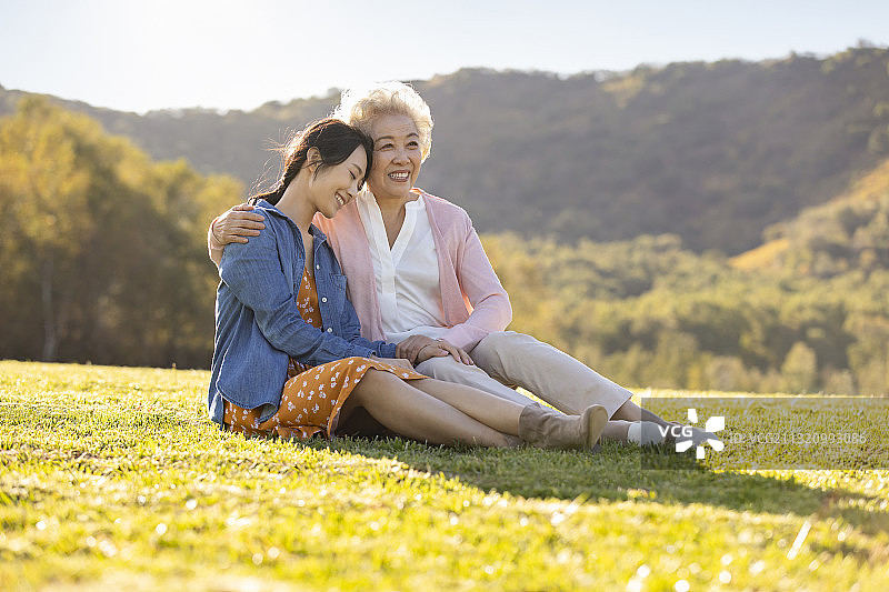 快乐的母女俩坐在草地上图片素材