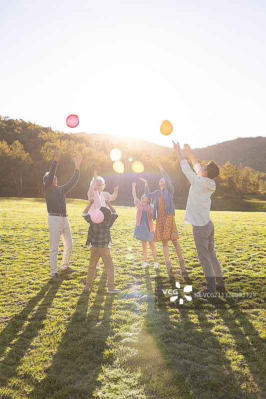 快乐的的六口之家在草地上玩气球图片素材